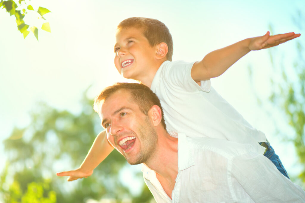 father with son on his back doing airplane arms